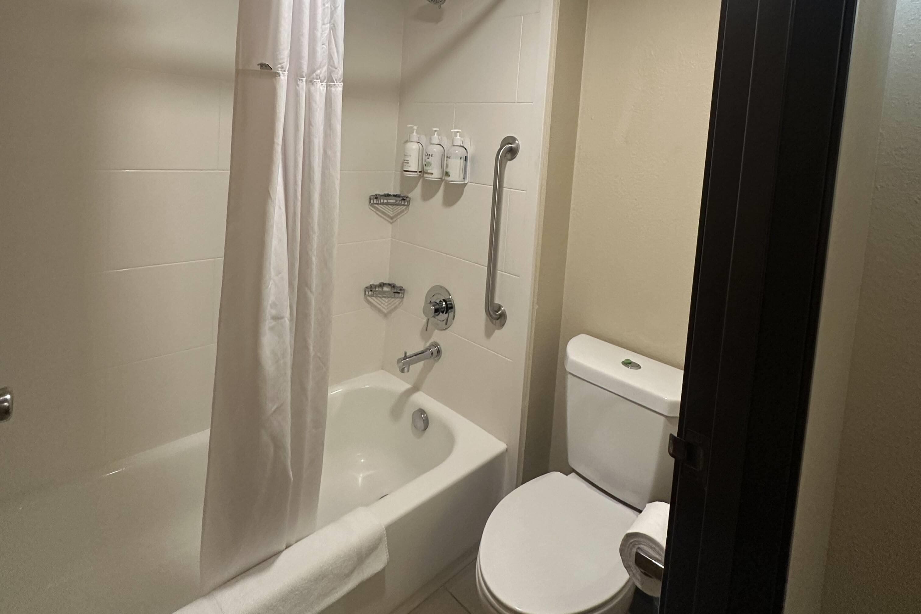 Een badkamer met een badkuip, toilet en handgrepen.