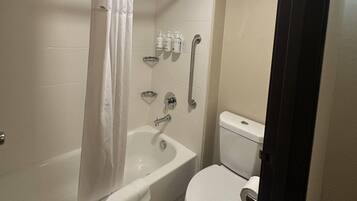 Een badkamer met een badkuip, toilet en handgrepen.