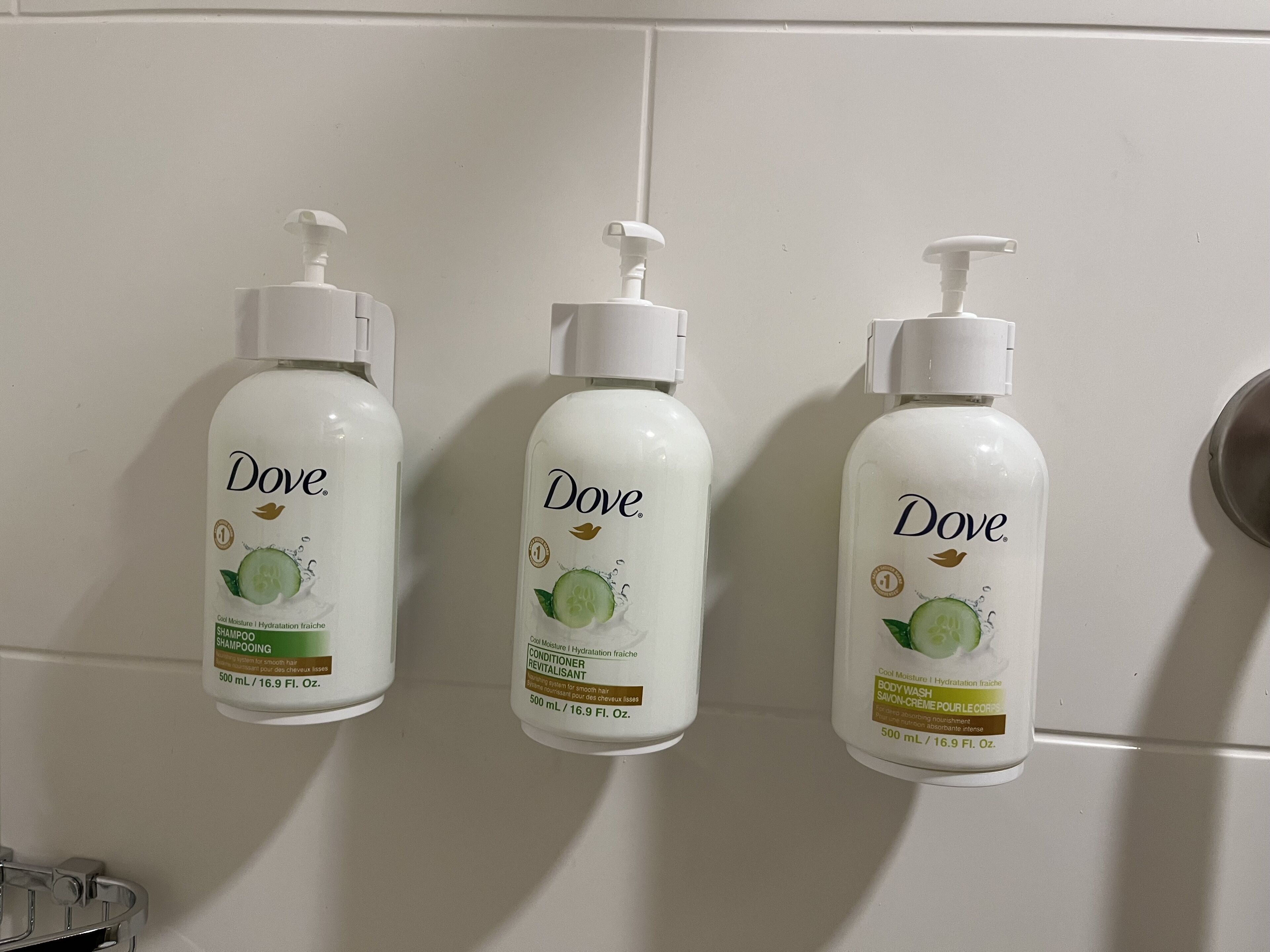Tre prodotti per la cura personale Dove su una parete del bagno.