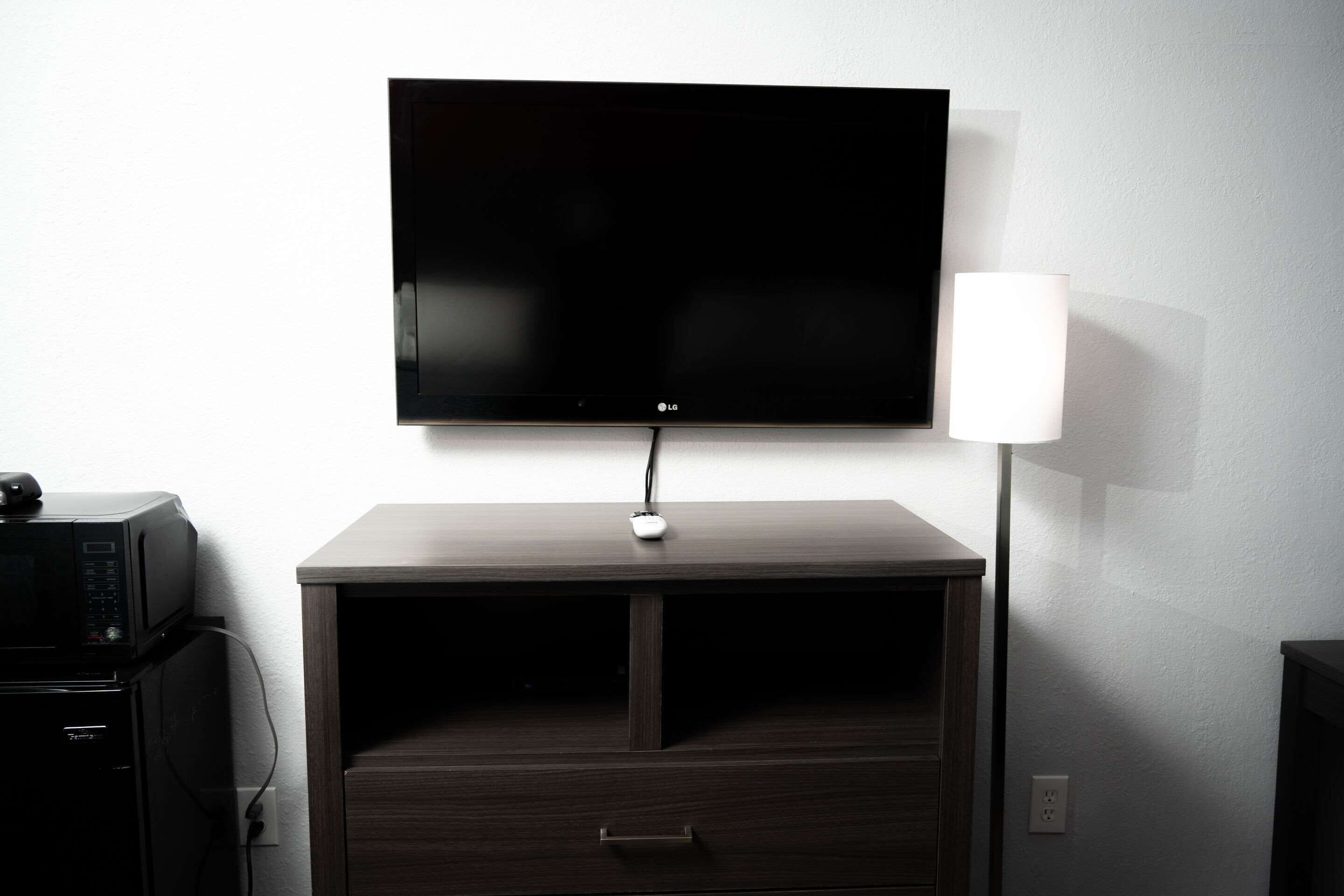 Un televisor de pantalla plana montado en una pared, sobre un mueble de madera con un cajón.