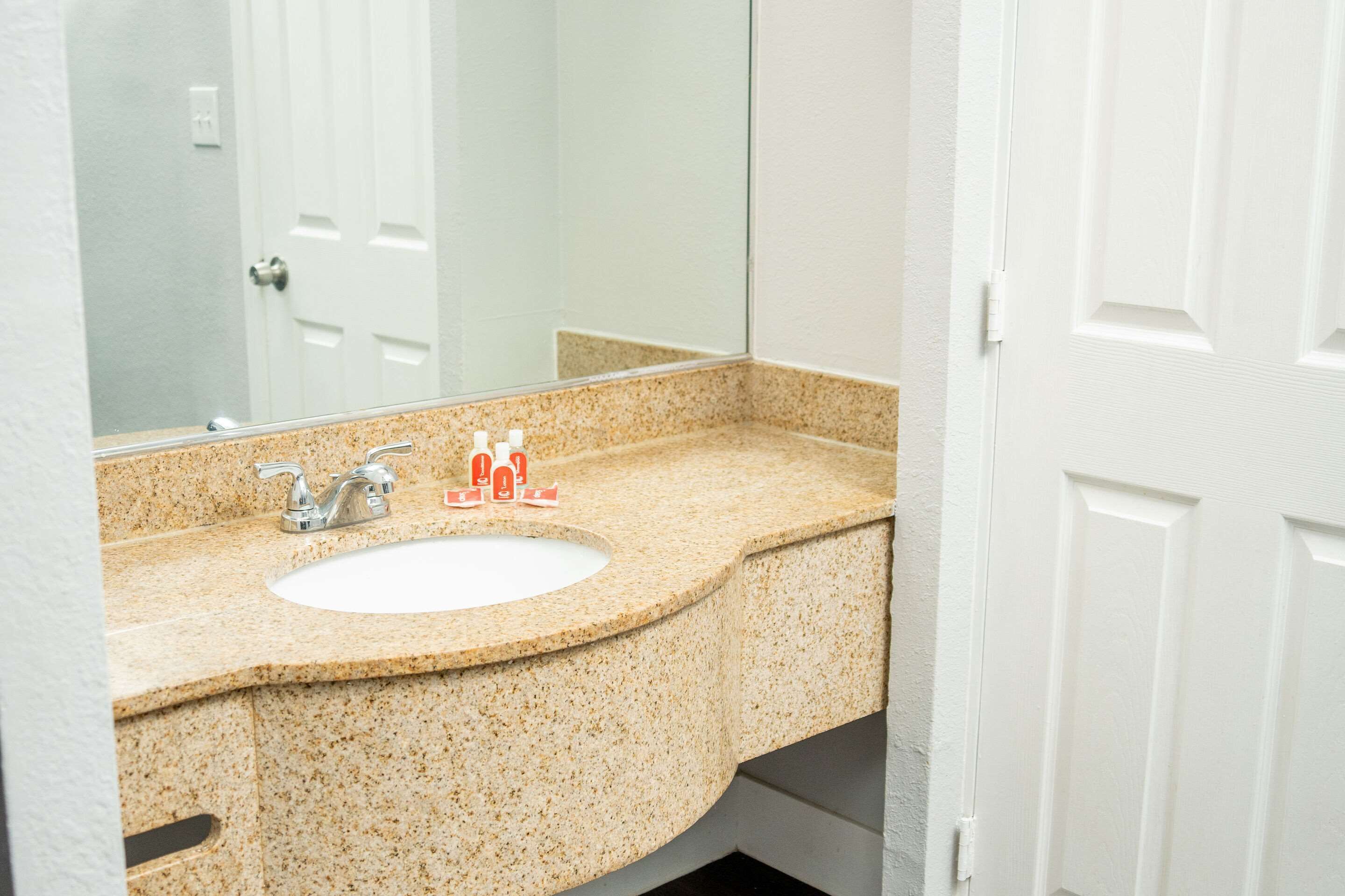 A bathroom with a granite countertop, a white sink, and a mirror.