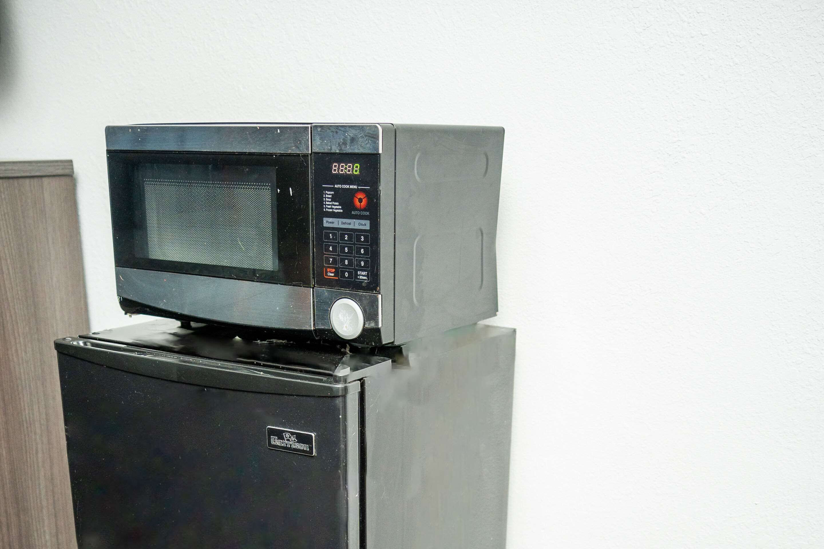 A microwave oven placed on top of a refrigerator.