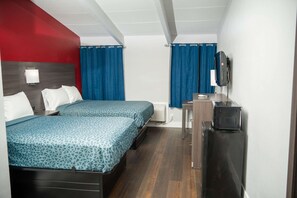 Habitación de hotel con dos camas, un escritorio, un televisor y una ventana con cortinas.