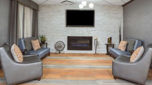 Una sala de estar moderna con dos sofás de cuero, una chimenea, un televisor de pantalla plana y un piso con estampado.