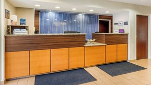 A reception desk with a wooden and orange design, a blue curtain, and a digital screen. - Fairfield Inn by Marriott Myrtle Beach North (Myrtle Beach)