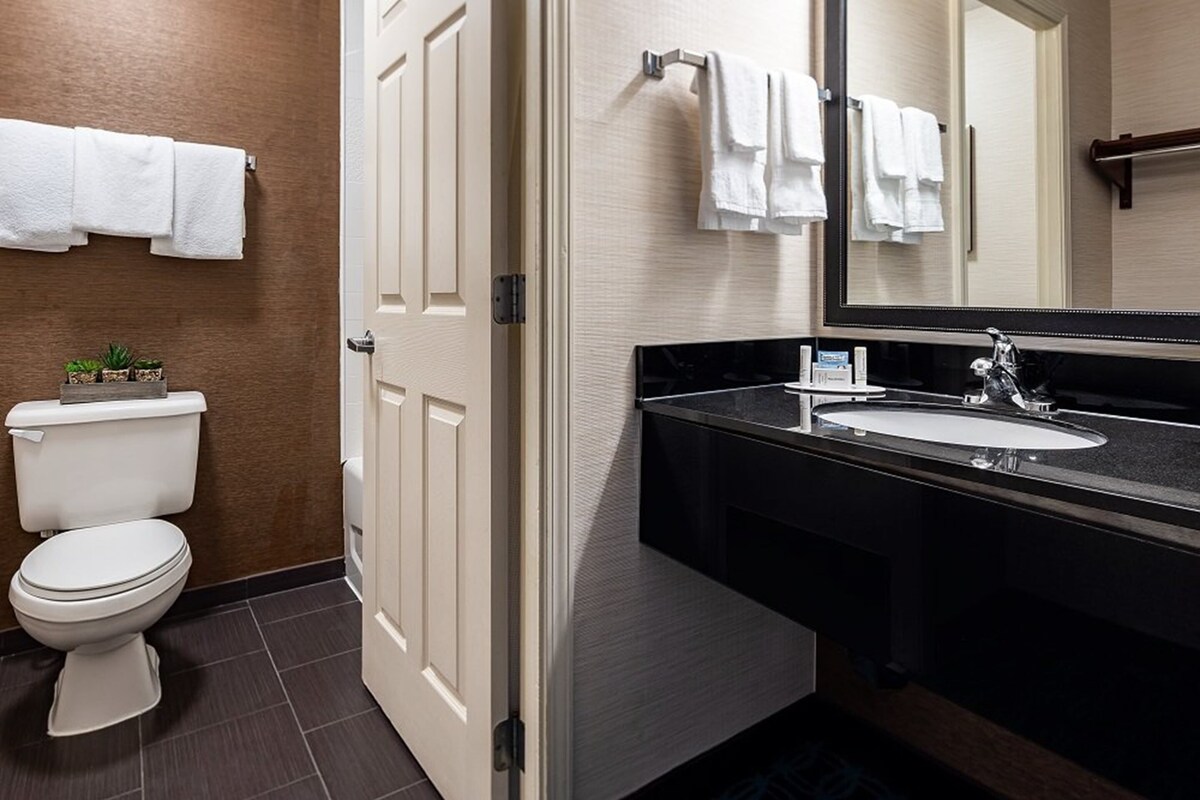 A modern bathroom with a toilet, sink, and mirror.