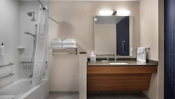 A modern bathroom with a bathtub, shower, vanity with a mirror, and a towel rack.