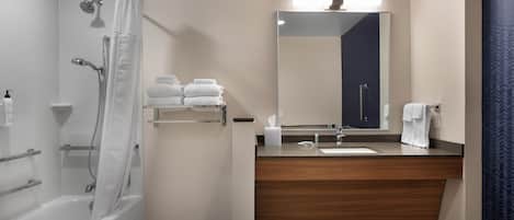 A modern bathroom with a bathtub, shower, vanity with a mirror, and a towel rack.
