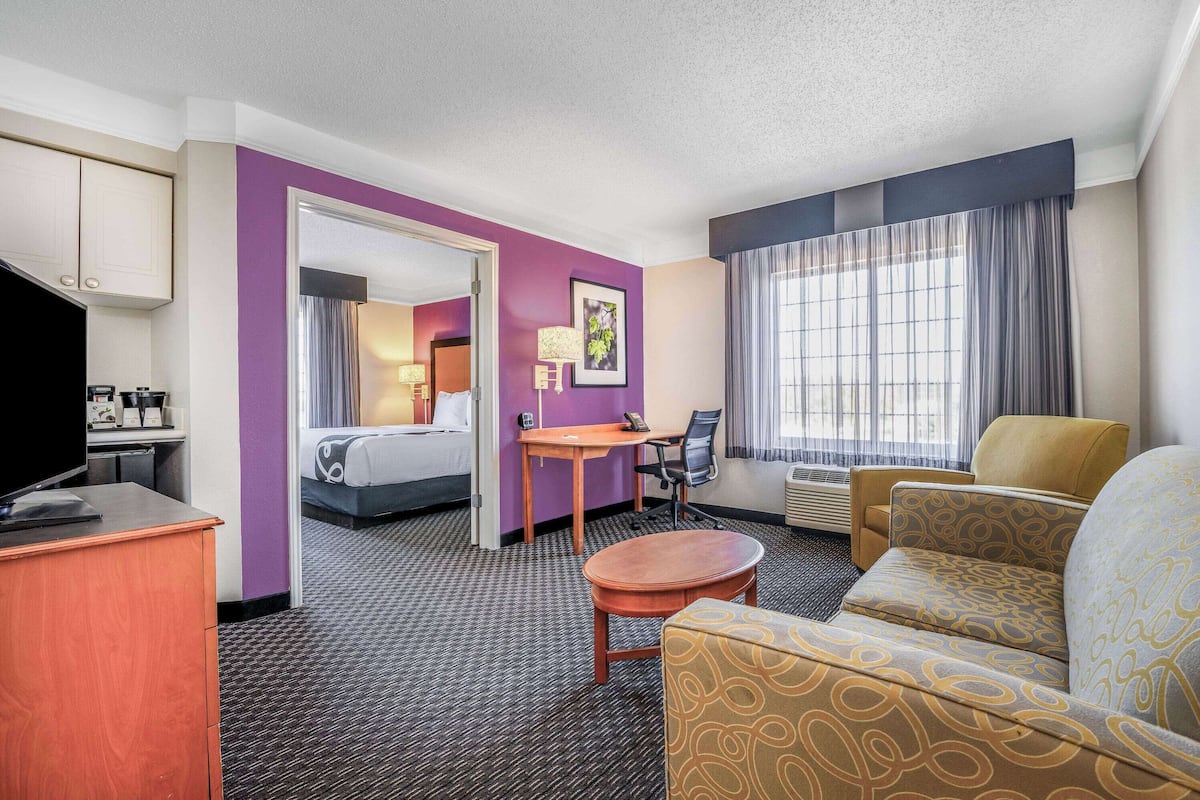 A hotel room with a bed, a desk, a chair, a sofa, and a television.