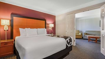 Una camera d'albergo con un letto grande, due comodini con lampade, un divano e un tavolino.
