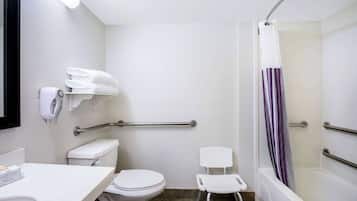 A bathroom with a toilet, a sink, a shower with a purple curtain, and a white chair.