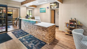 A reception area with a wooden reception desk, a laptop, and a sign for 'EverSpring Inn & Suites'. - EverSpring Inn & Suites (Hill City)
