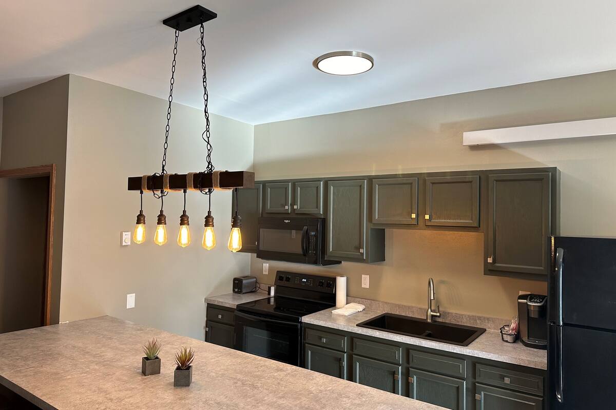 A modern kitchen with a central island, built-in appliances, and pendant lighting.