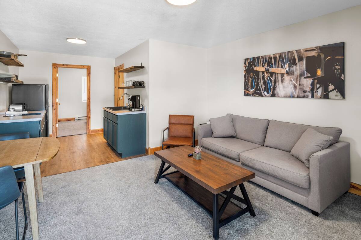 A compact living space with a dining area, a sofa, a coffee table, and a kitchenette.