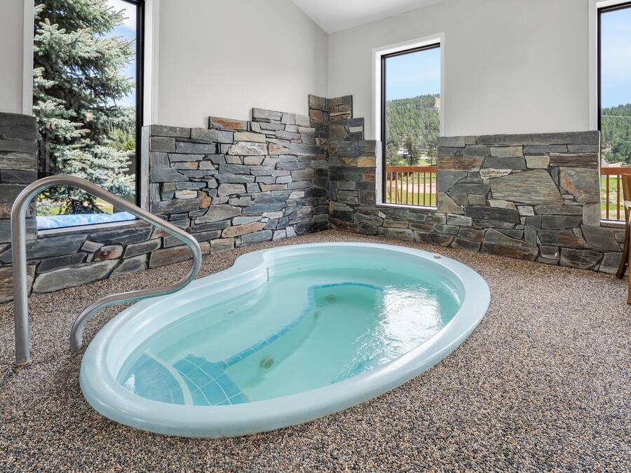Una piscina interior con paredes de piedra y vistas a una zona boscosa.