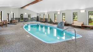 A large indoor swimming pool with stone walls, wooden benches, and a stone staircase. - EverSpring Inn & Suites (Hill City)