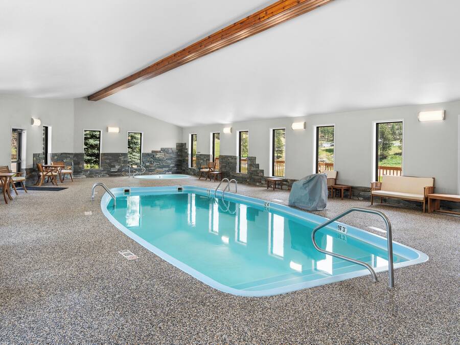 Ein großes Hallenbad mit Steinwänden, Holzbanken und einer Steintreppe.