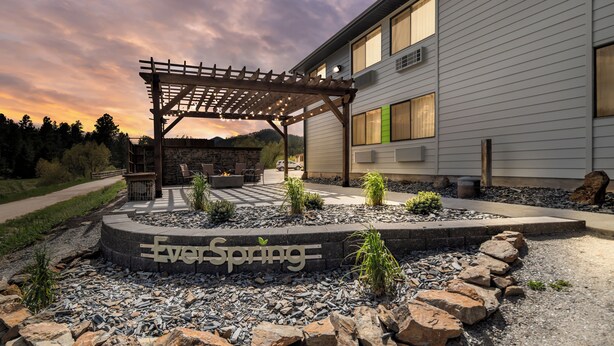 A modern building with a pergola and outdoor seating area. - EverSpring Inn & Suites (Hill City)