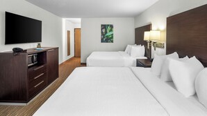 A hotel room with two beds, a TV, a desk with a lamp, and a painting on the wall. - EverSpring Inn & Suites (Hill City)