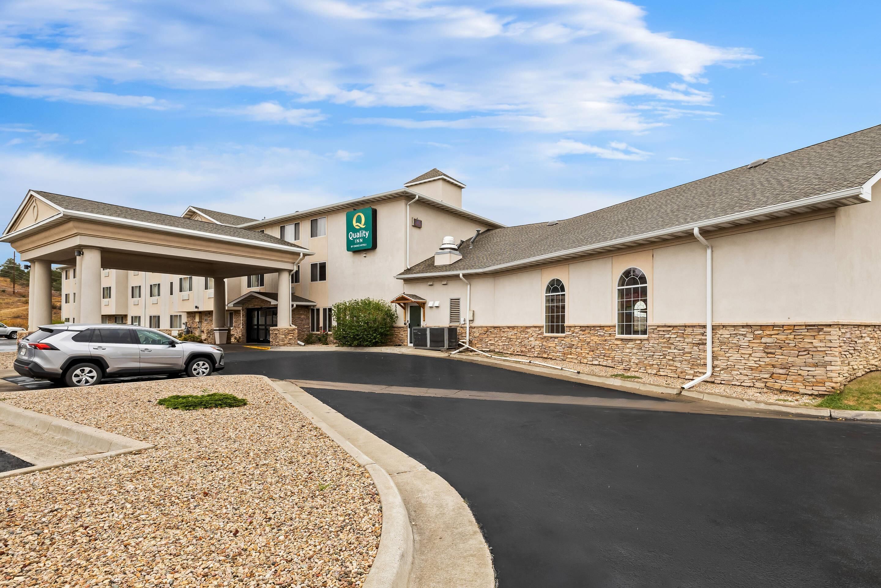 A hotel with a covered entrance, a stone facade, and a sign for Quality Inn.