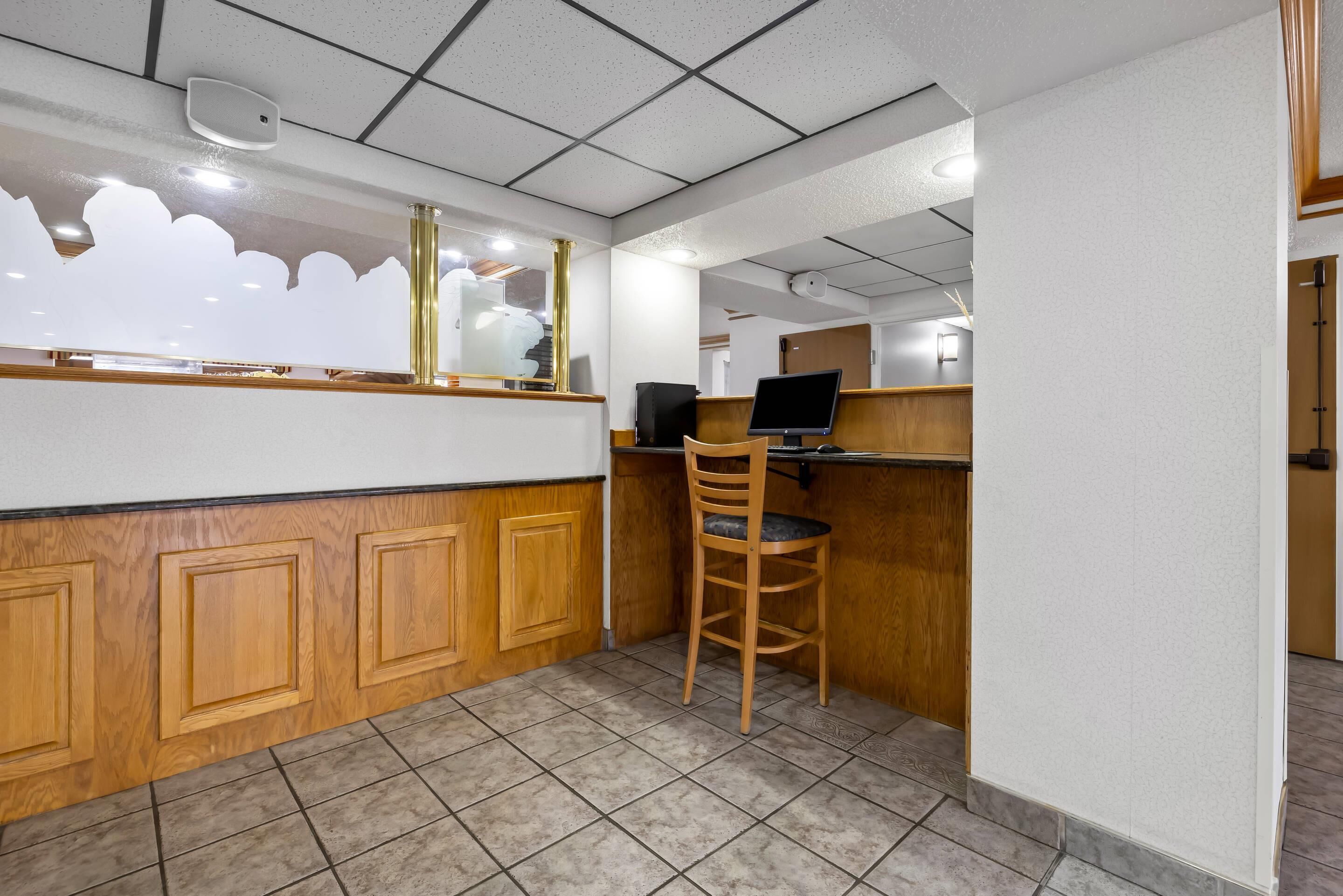 A reception area with a wooden counter, a computer, and a chair.
