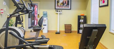A gym with exercise equipment, a water dispenser, and a wall-mounted picture.