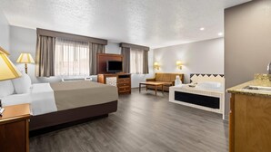 Habitación de hotel con cama, televisor, escritorio, silla, sofá, mesita y baño con bañera y lavamanos.