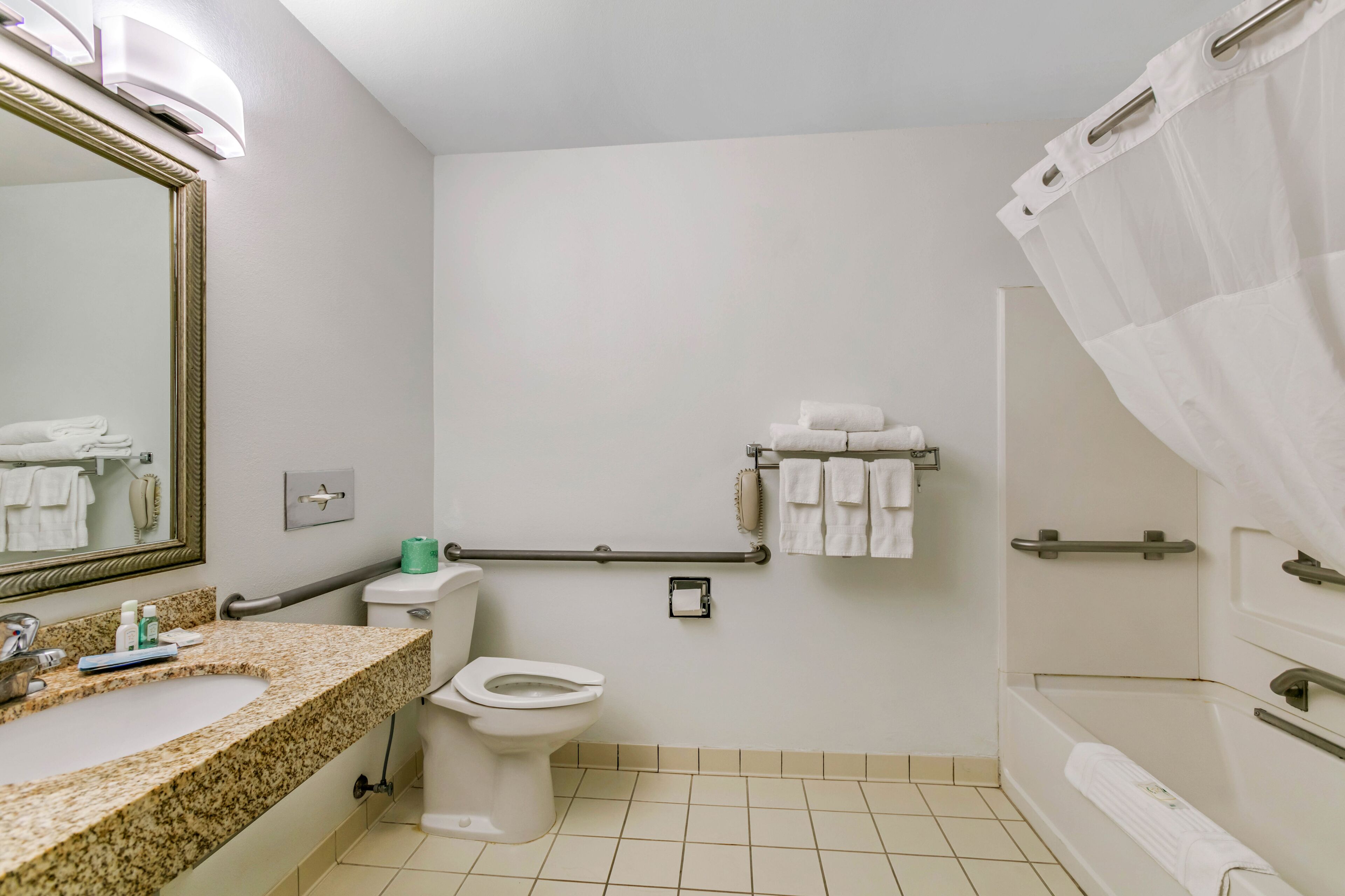 A bathroom with a sink, toilet, and bathtub. There are handrails and a towel rack.