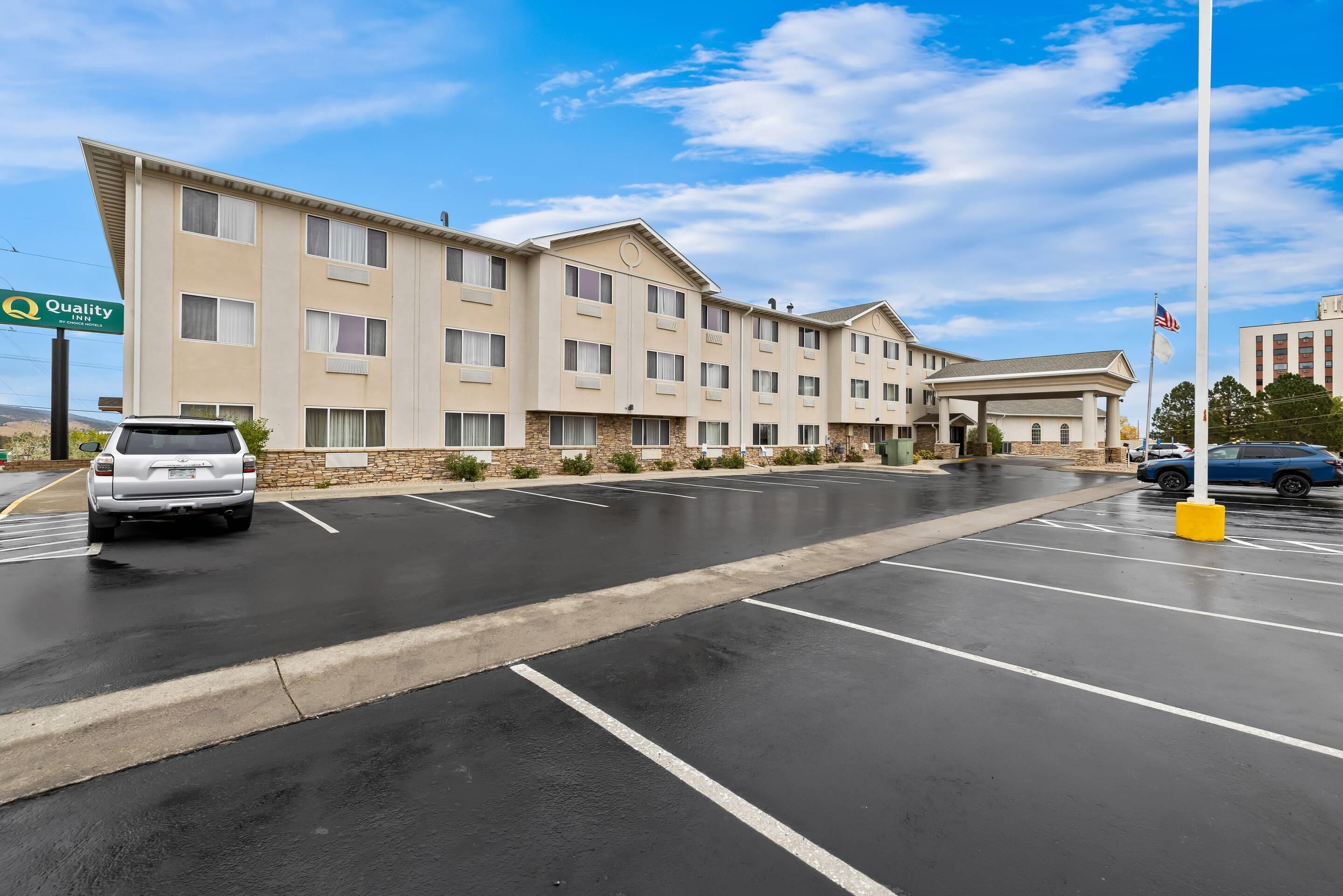 A hotel with a parking lot and a clear sky.