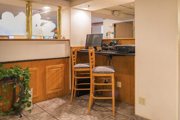 A small, clean room with two wooden chairs, a desk with a computer, and a mirror on the wall.