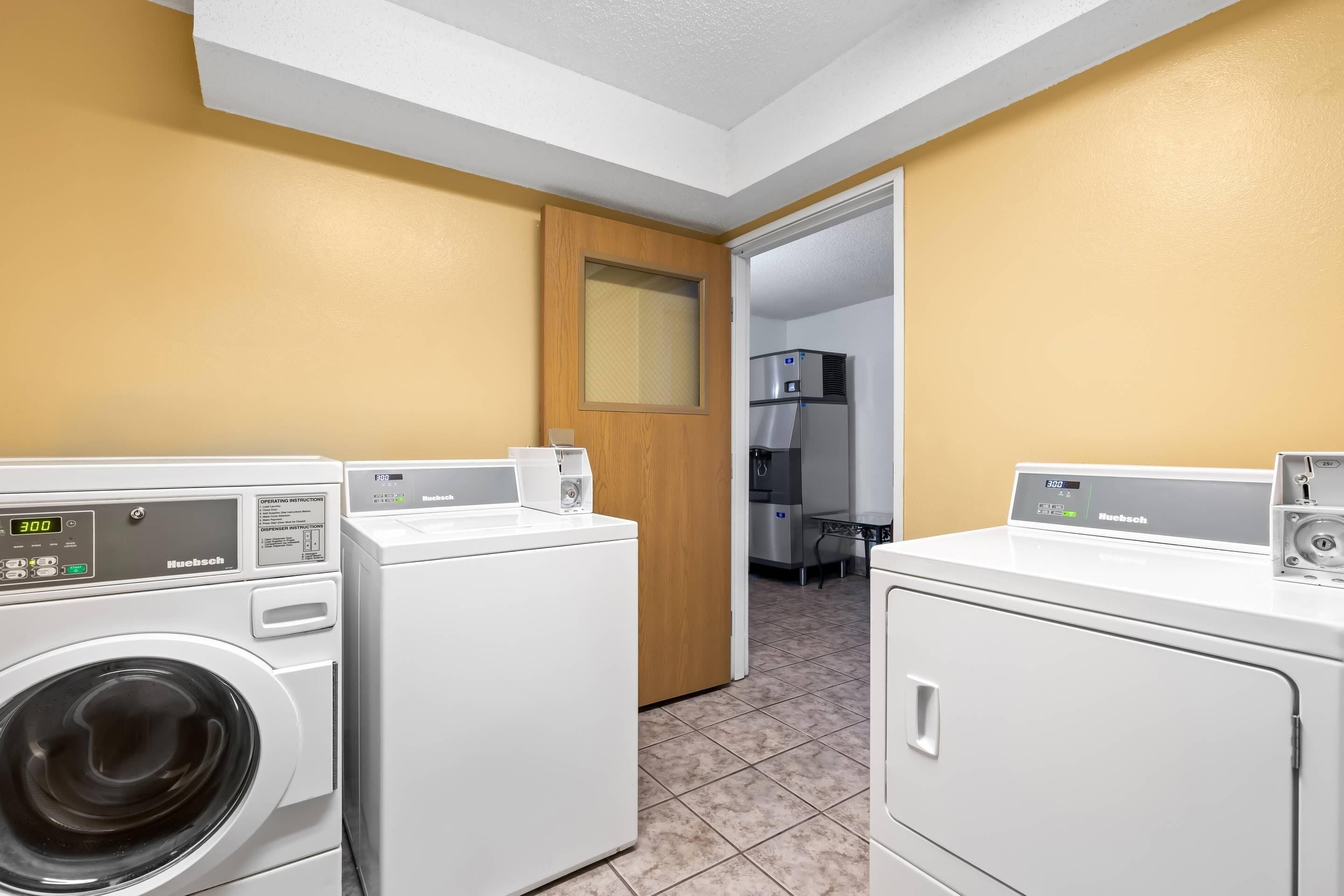 A laundry room with two front-loading washing machines, a dryer, and a microwave.