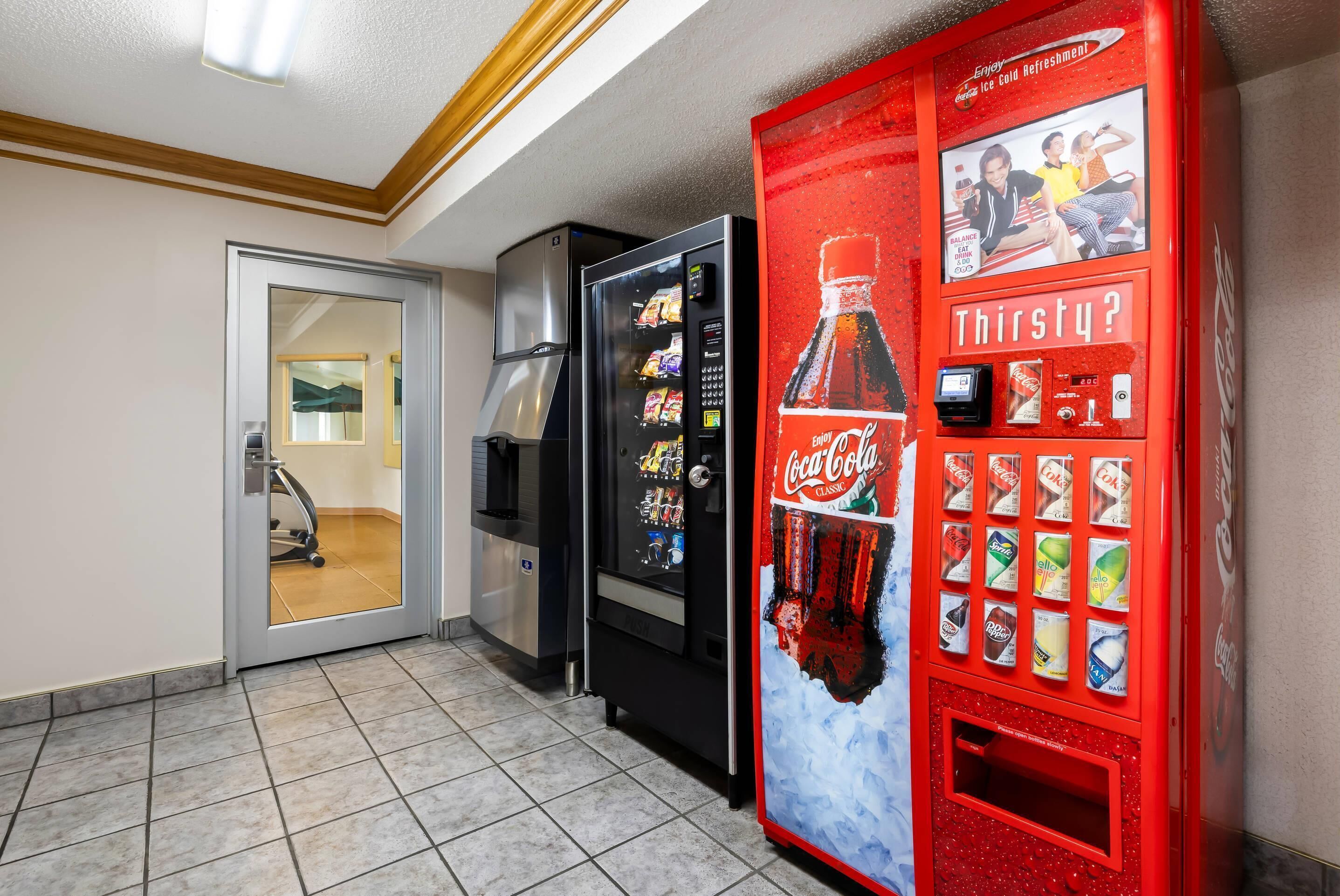 A vending machine area with a Coca-Cola branded machine and a refrigerator.