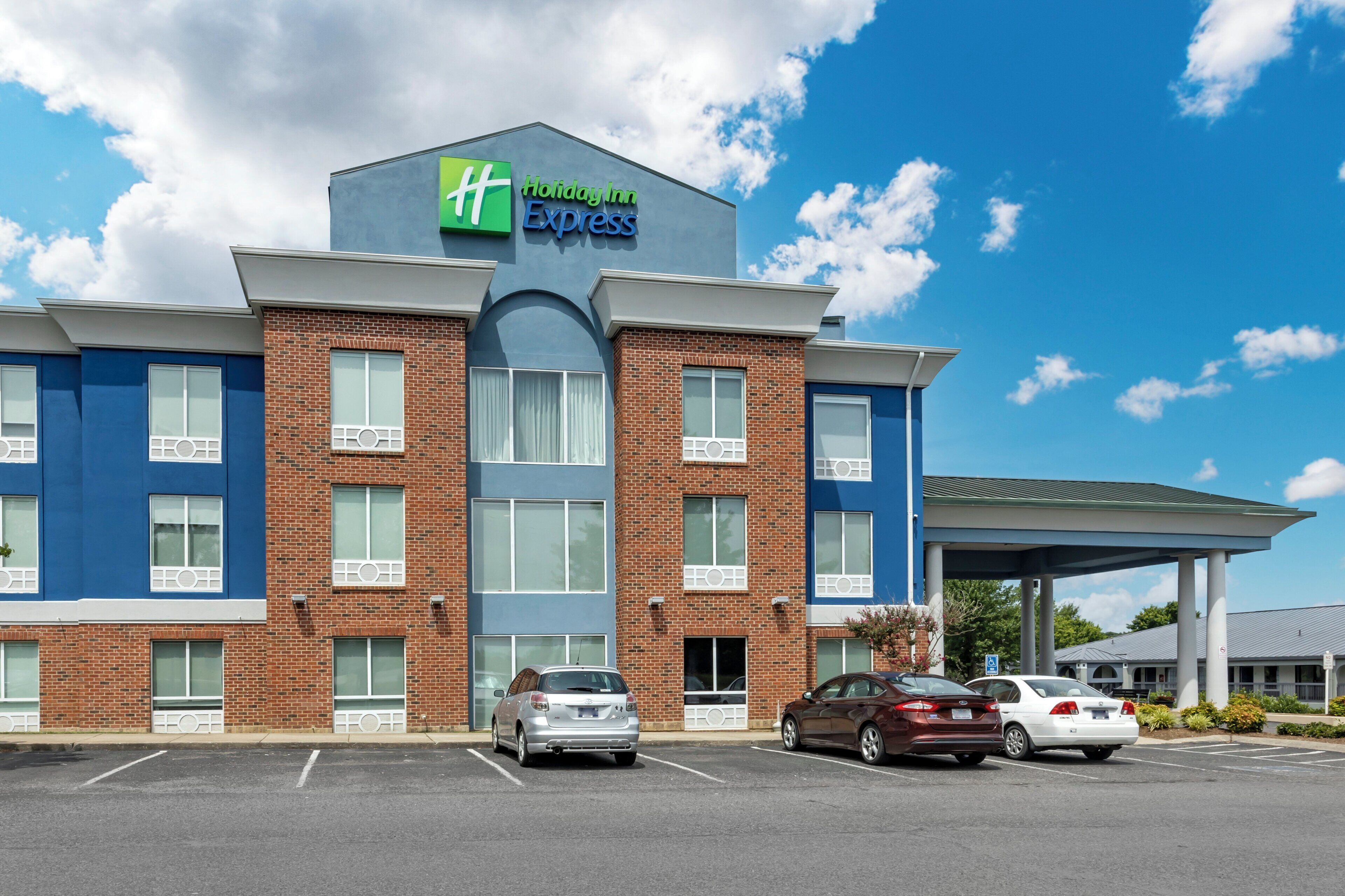 Een Holiday Inn Express gebouw met een bakstenen gevel, grote ramen en een overdekte parkeerplaats.