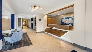 A modern reception area with a wooden reception desk, seating area with chairs, and a corridor leading to other rooms.