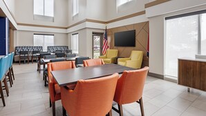 A conference room with a large table and chairs, an American flag, and a TV on the wall.