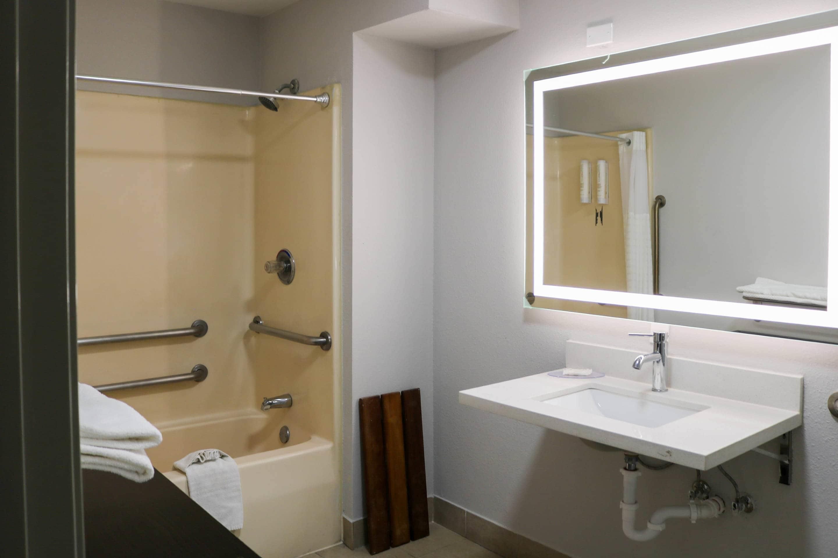 A bathroom with a bathtub, a sink, and a mirror.