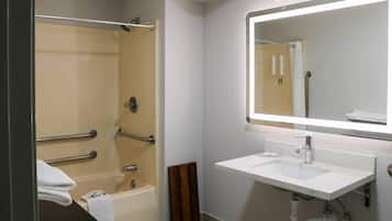 A bathroom with a bathtub, a sink, and a mirror.