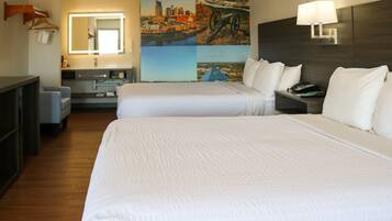 A hotel room with two beds, a desk, a chair, a bathroom, and a cityscape view.
