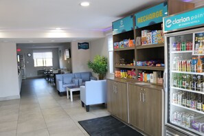 A hotel lobby with seating, a kitchenette, and a minibar stocked with beverages and snacks. - Clarion Pointe (La Vergne)