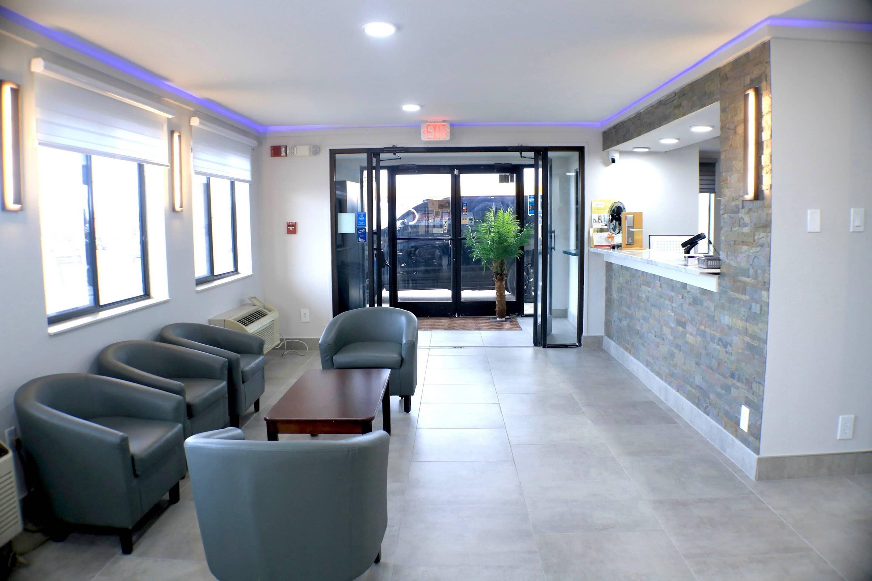 A reception area with a counter, a seating area with chairs, and a view through the glass doors.