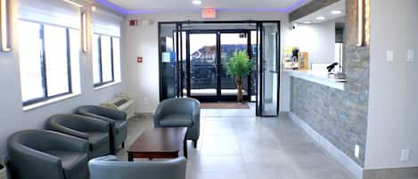 A reception area with a counter, a seating area with chairs, and a view through the glass doors.