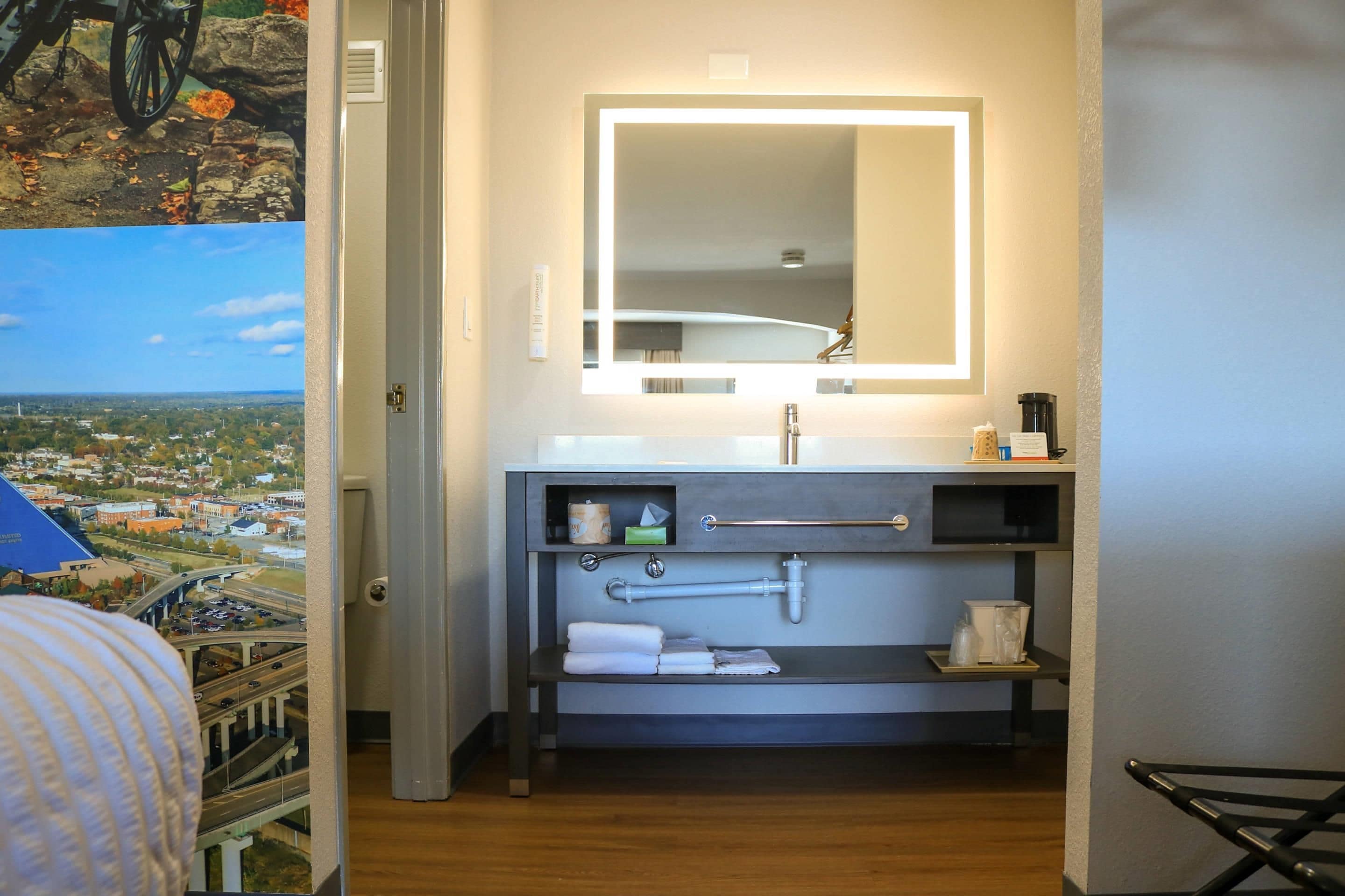 Une salle de bain d’hôtel avec un grand miroir, un lavabo et un porte-serviettes.