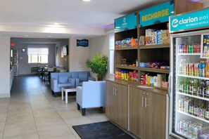 A hotel lobby with a seating area, a refrigerator stocked with beverages, and a wall sign indicating a starting point. - Clarion Pointe (La Vergne)