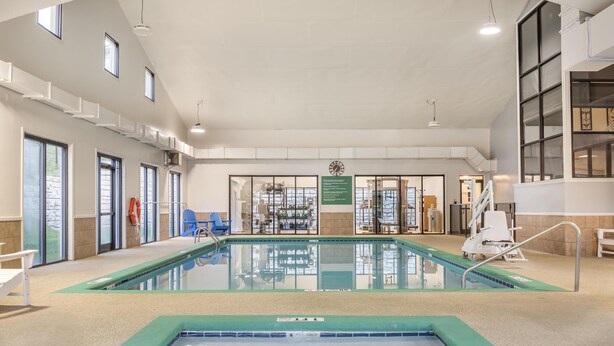 Ein Innenpool mit klarem Wasser, umgeben von Fliesenboden und -wänden, und einer Decke mit natürlichem Licht durch Fenster.