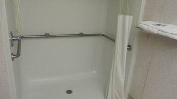 A shower area with a grab bar, a white towel rack, and a tiled floor.