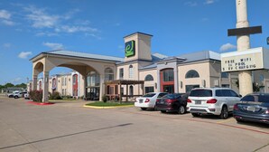 A hotel with a modern design, featuring a prominent entrance with an archway, a sign indicating free WiFi and EV charging, and several parked cars. - Executive Inn and Suites Wichita Falls (Wichita Falls)