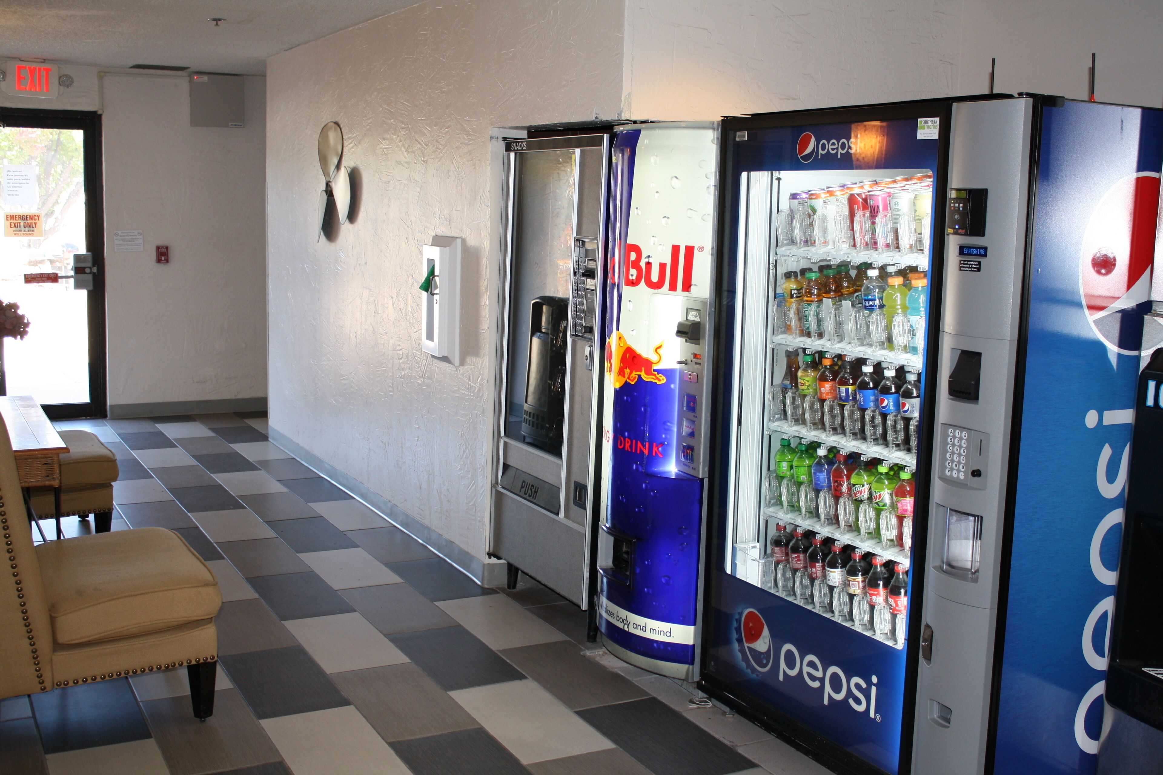 A vending area with Pepsi and Red Bull machines, a checkered floor, and a table with chairs.