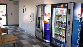 A vending area with Pepsi and Red Bull machines, a checkered floor, and a table with chairs.