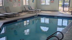 An indoor swimming pool with lounge chairs and safety signs on the walls. - Executive Inn and Suites Wichita Falls (Wichita Falls)