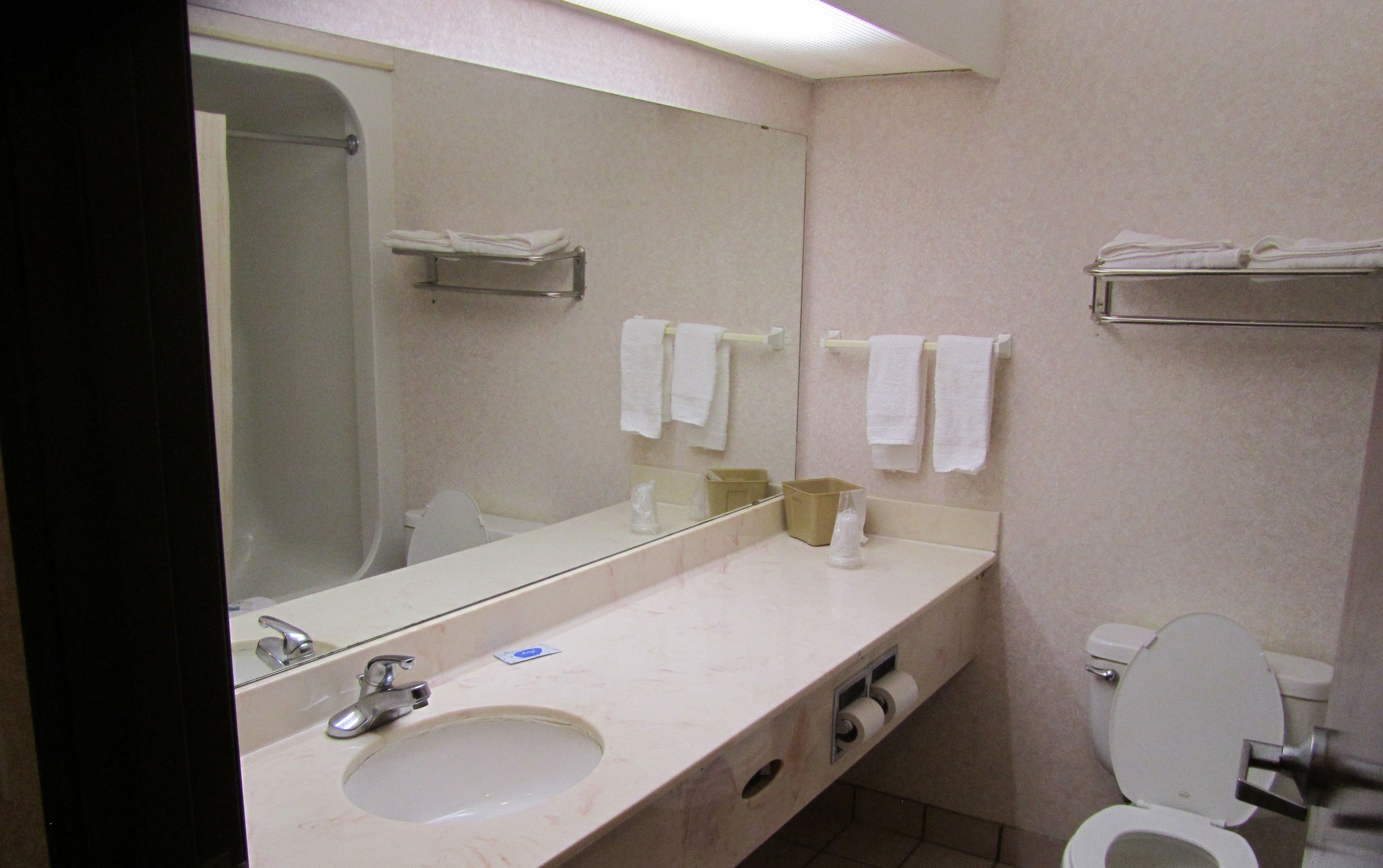A bathroom with a sink, mirror, towel rack, and toilet.